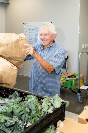 NeighborImpact Volunteer Vern Bjerk packs Fresh Express home deliveries.