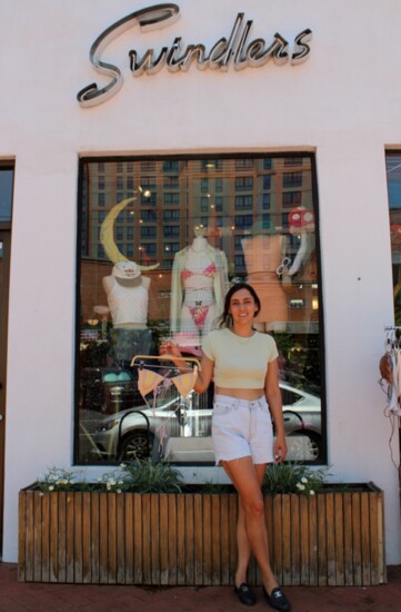 Swindlers boutique owner Christina Henneke poses in front of her storefront holding a bikini top made by Elizabeth Barclay. Henneke's favorite summer trend is c