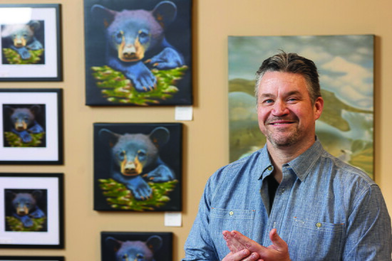 Brett Mistak stands in front of prints of his painting "Scratch"