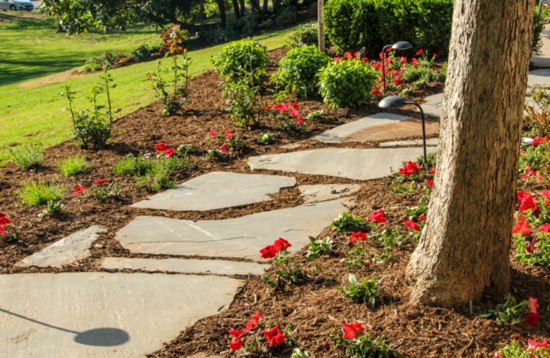 Flower gardens line the pathway wrapping around the south end of the home.