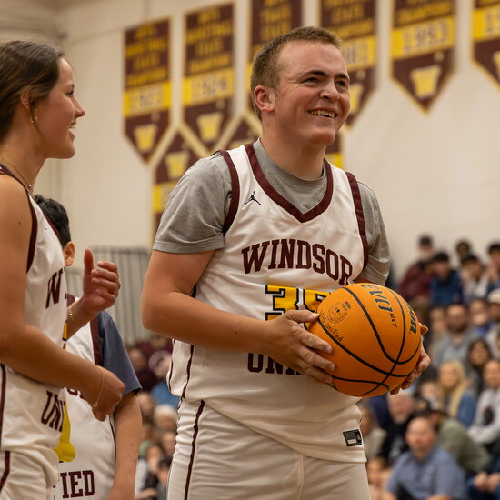 Unified Athlete Riley locks eyes on the basket, guided by Unified Mentor Mia at the annual Windsor High School Unified Showcase Basketball game.