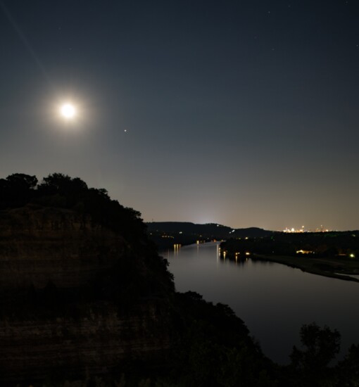 The moon glows bright over Lake Austin and downtown