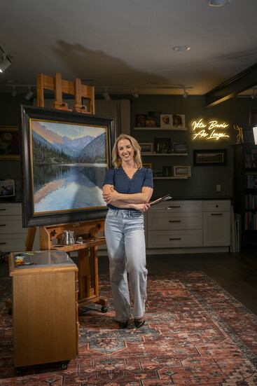 Anna in her studio with her painting Dusk at Mills Lake