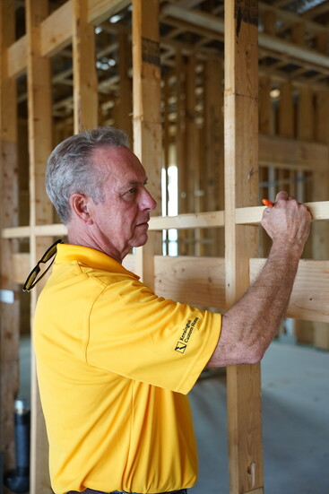 Kensington Custom Homes' Nick Smith signs one of the framing boards in a home he is building in Carillon Parc.