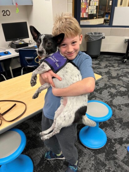 A student hugging a Caring Canine therapy dog.