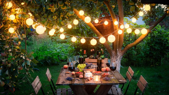 Outdoor dining table with food and lighting.