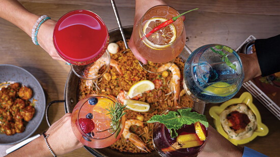 Raised glasses over Telefèric Barcelona’s iconic Paella Mixta and signature cocktails.