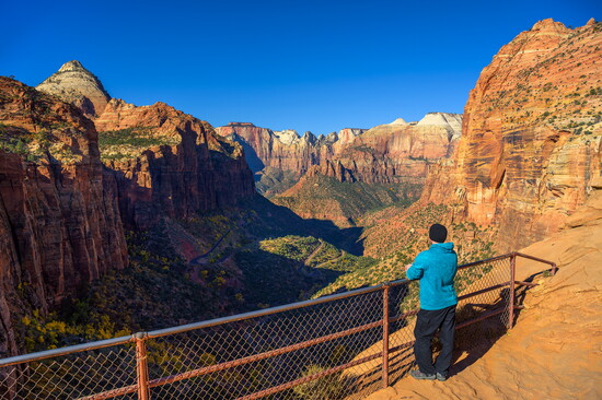A tourist admires the scenic view of Zion Canyon from Canyon Overlook in Zion National Park