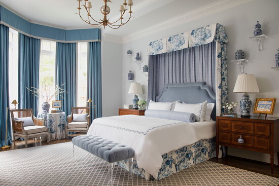 A custom - made drapery canopy and upholstered headboard were designed for this primary bedroom by Lindsey Herod. Styled by Curious Details