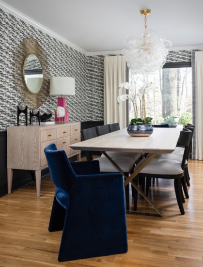 For this Potomac, MD home, the whimsical wallpaper is complemented by the fun pop of pink lamp and textured blue velvet chairs.