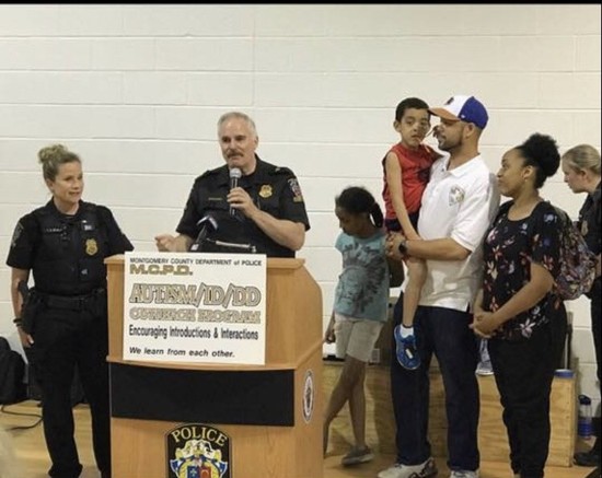 Officer Laurie Reyes (left) is with former MCPD Chief Tom Manger (at the podium), as they honor the Goldman family. 