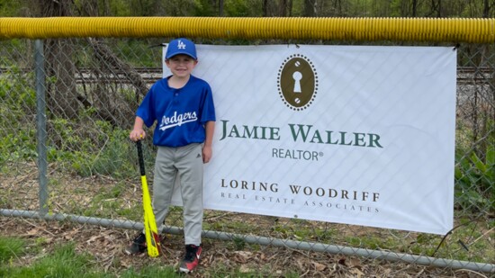 Jamie Waller's son posing in front of a Jamie Waller sponsorship banner. Photo Credit: Jamie Waller.