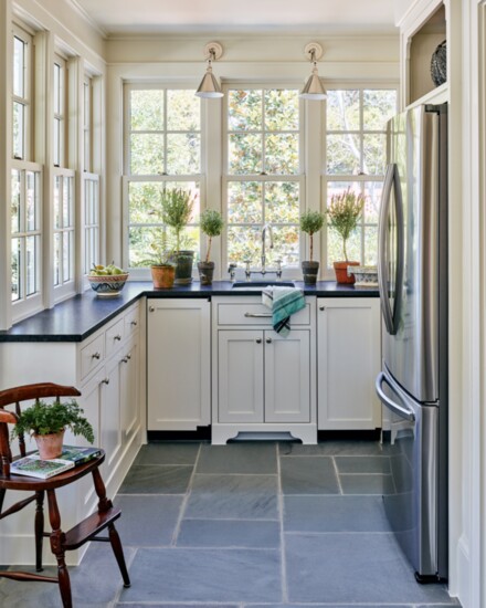 The bluestone floors in the cottage kitchen are a durable surface for poolside entertaining. The antique highchair is a family heirloom of the homeowners.