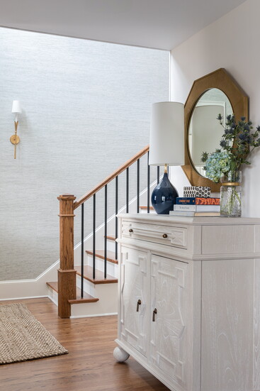A Gabby chest, sleek Visual Comfort lighting, and textured Cowtan & Tout grasscloth bring elegance and warmth to the foyer