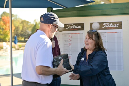 Chamber staff member Cereto Bean hands out prizes at the Chamber Golf Tournament. Photo by Gobi Photography