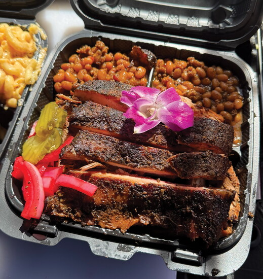 Smoked barbecue ribs served with baked beans and pickles.