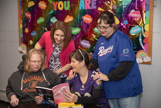 Laura Weinstein (standing, in pink) and Joy Barton (seated in Ravens jersey) with two participants at Harford Center. Photo Credit: Kerry Paradis Photography