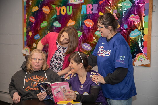 Laura Weinstein (standing, in pink) and Joy Barton (seated in Ravens jersey) with two participants at Harford Center. Photo Credit: Kerry Paradis Photography