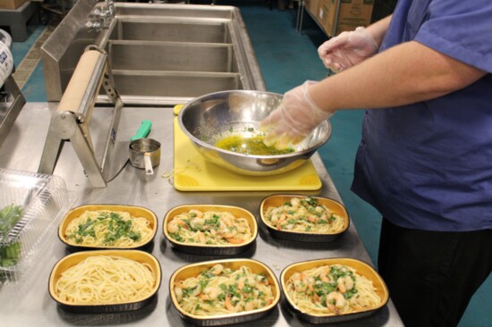A worker in the Seafood Department prepares shrimp scampi that can be heated at home. 