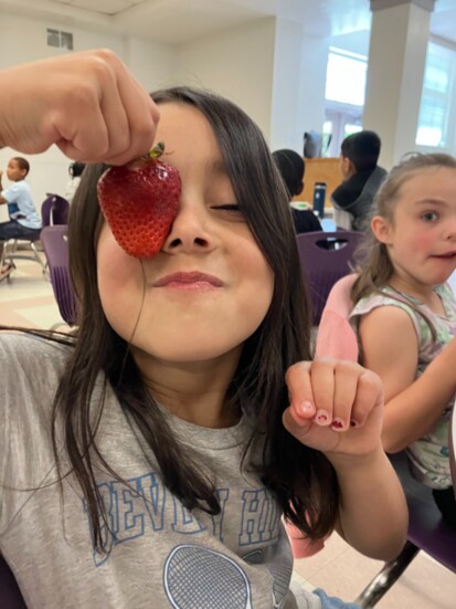 Student enjoying a strawberry during Harvest of the Month. Photo credit: Aleen Carey 