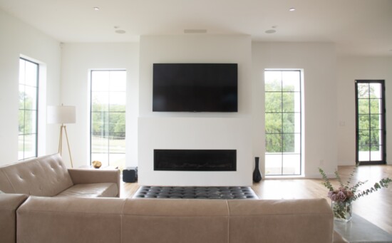 The living room’s non-traditional mantle is a sleek, smooth ledge above a minimalistic, modern approach to the fireplace.