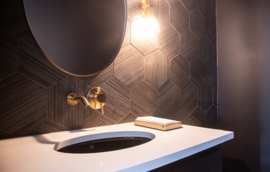 Powder rooms are perfect places to take risks, says Harper. Moody and darker in floor-to-ceiling tile with trendy shades of black and gold 