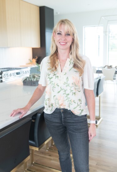 Texas architect Sarah Harper smiling with pride next to the kitchen island in the new home that she designed for her family