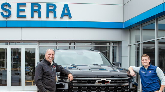 Father and son team Barry and Zac Carver pose by a Chevrolet truck at their dealership.