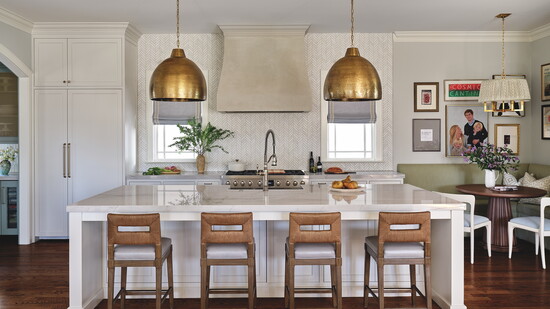 The kitchen features a quartzite countertop, custom-made plaster hood, brass dome lighting from Currey & Company and jute-wrapped Palecek counter stools