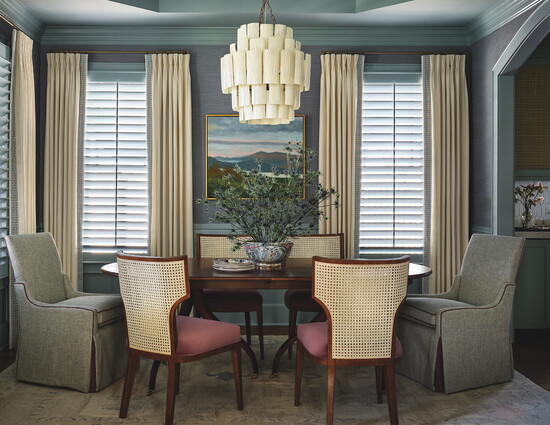 The dining room is color-drenched in Sherwin-Williams Stardew blue and features a Marjorie Chandelier in resin-coated banana bark from Made Goods. The painting 