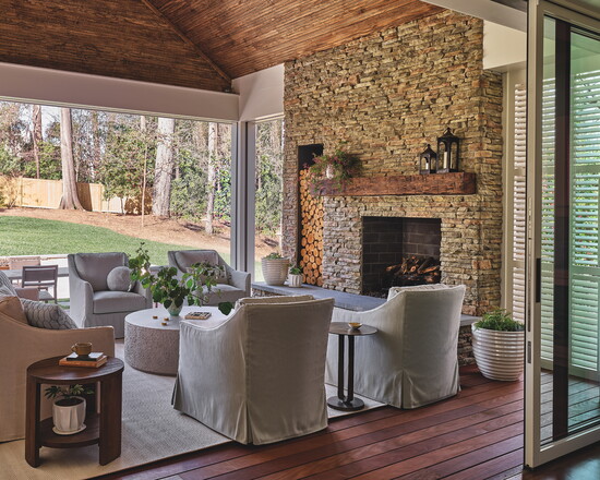 A covered porch featuring a stacked stone fireplace extends to the outdoor patio, creating ideal space for indoor/outdoor entertaining. The patio features a 