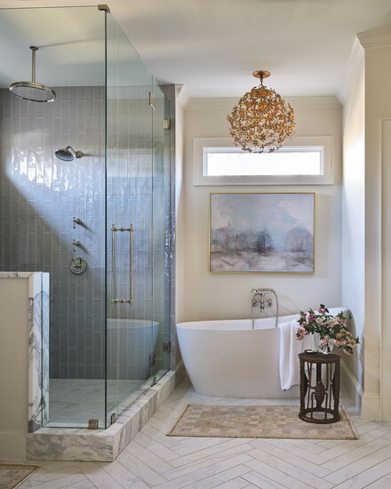 Primary bathroom chandelier by Currey & Co. The shower was squared off, and the knee wall was added to hide the niche and products.