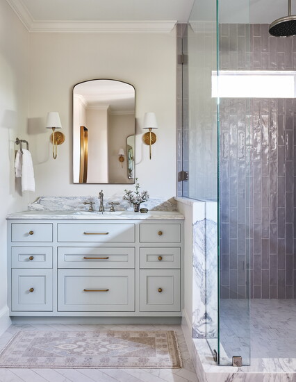 Decorative splash accents a marble slab from Walker Zanger that was fabricated by Harkey. Cabinetry is lit from the bottom and features pullouts for hot tools.