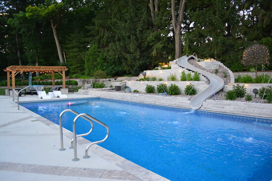 Elm Grove Private Retreat: An aging concrete pool was replaced with a redesigned lower-level pool, waterslide, pergola, and lounge area.