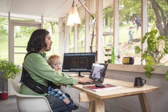 With a second monitor to entertain his son, this new work station allows Nathan Webb to watch his other son at play outside