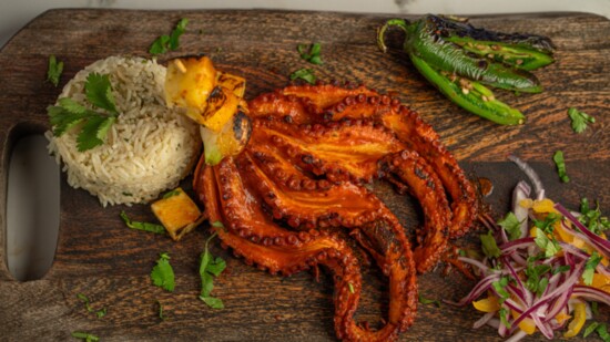 Pulpo al Pastor is a King Corona specialty dish of chargrilled octopus served with grilled pineapple, chambray onion, roasted jalapeno + arroz de coco
