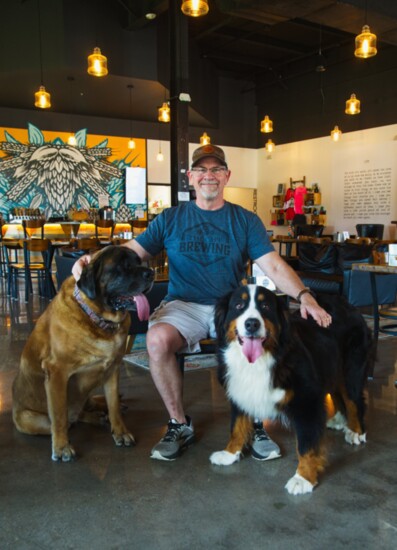 Cape Brewing Co Founder JC Cody poses with his dogs Millie and Lady. Photo Acrylic Asylum Art.