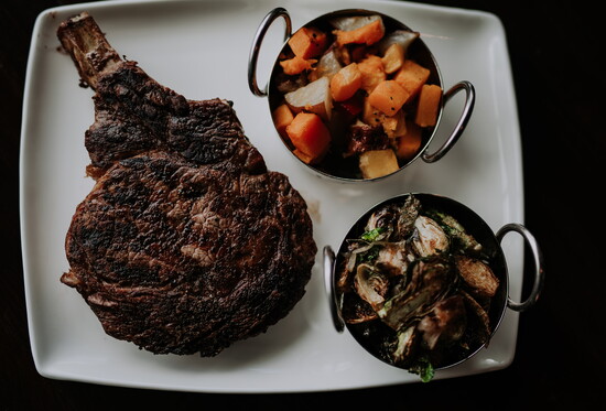 Enjoy the quintessential gentlemen's meal by indulging in The Refuge's wood-grilled Cowboy Ribeye. Photo Credit: Minerva House for The Refuge.