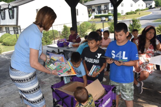 Irene delivering books to a group of children.