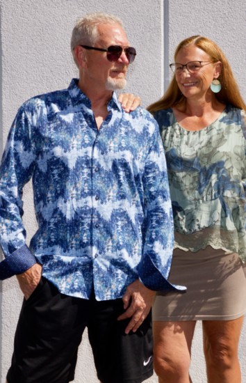 Brian S: blue patterned shirt by Mizumi; sunglasses by Adorro. Sue: blue & green floral blouse, Tempo; taupe body hugging dress, MRena; earrings, Meghan Browne