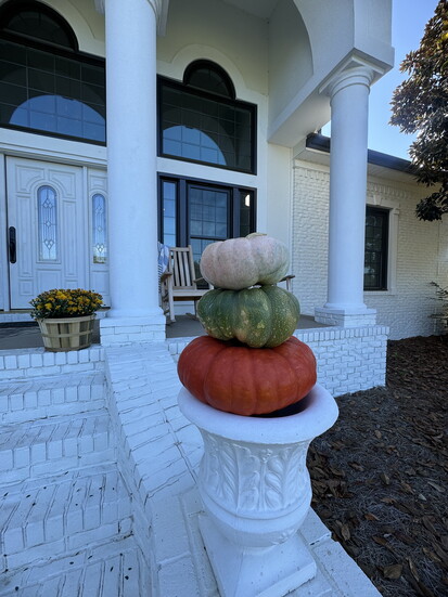 Stacked pumpkins, mums and a cozy rocking chair create a welcoming atmosphere.