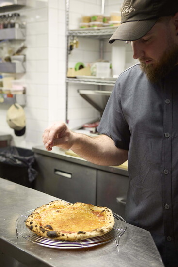Executive chef Zach Hinman puts the finishing touches on a pizza.
