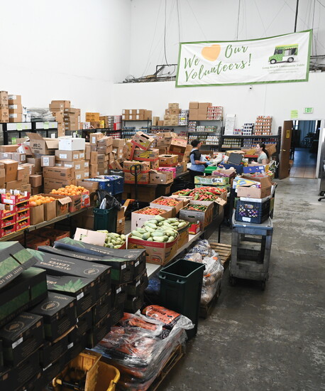 Inside the LBCT warehouse, tables and shelves are stocked with produce and nonperishable goods awaiting distribution.