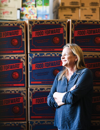 Kristen Cox, founder and executive director of LBCT, poses among boxes of produce and donated goods at the organization’s warehouse.