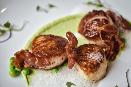 Seared scallops served with pea puree, crispy Spanish Serrano ham and lemon foam.