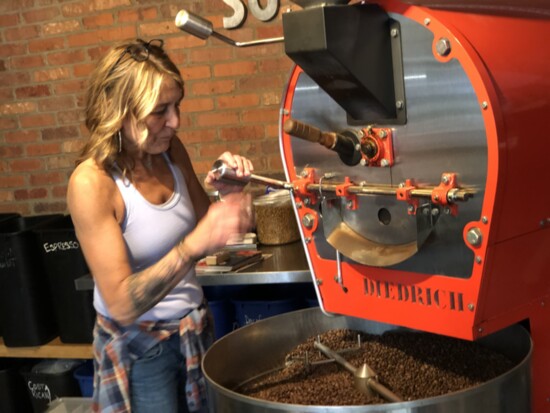 Karen monitors coffee beans roasting inside So. G's new roaster. 