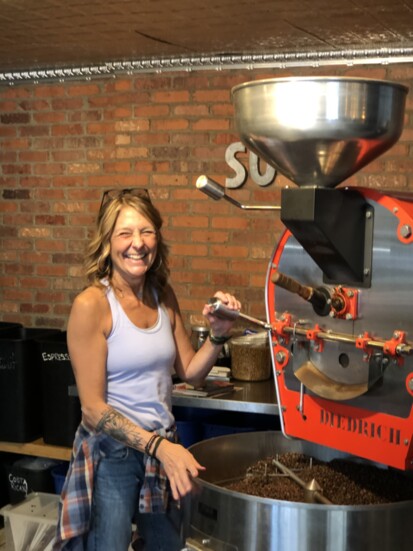 Karen shows a visitor the large coffee roaster inside So. G Coffee in South Glastonbury. 