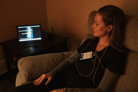 Balance Health patient relaxes in the dim-lit feedback room, listening to soothing music