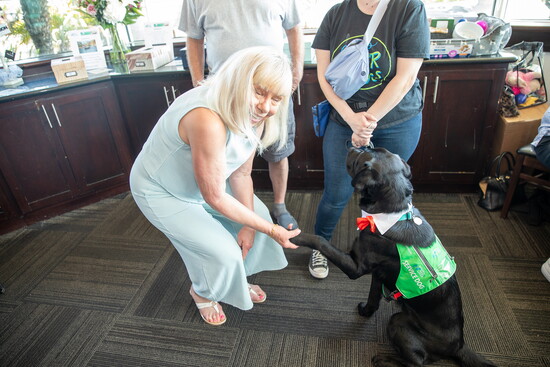 Sherri Foster shakes the paw of a service dog.