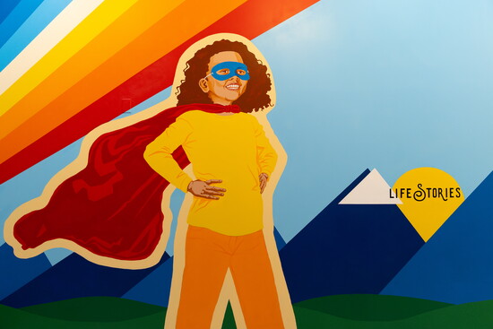 Emerging from darkness into light, this mural reflects courage, healing, and the strength children show by sharing their stories.